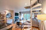 Experience modern living in this stunning multi-level apartment, featuring a striking spiral staircase that connects the open-concept living and dining areas.