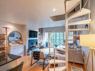 Experience modern living in this stunning multi-level apartment, featuring a striking spiral staircase that connects the open-concept living and dining areas.