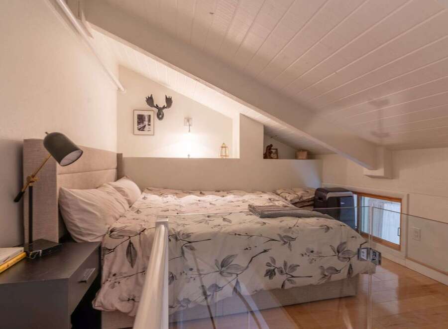 Discover this charming loft bedroom, featuring a comfortable bed with a floral-patterned duvet and a stylish headboard.