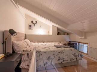 Discover this charming loft bedroom, featuring a comfortable bed with a floral-patterned duvet and a stylish headboard.