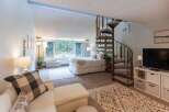 Discover this charming studio apartment featuring a cozy bed area with large windows offering serene forest views.