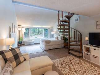 Discover this charming studio apartment featuring a cozy bed area with large windows offering serene forest views.