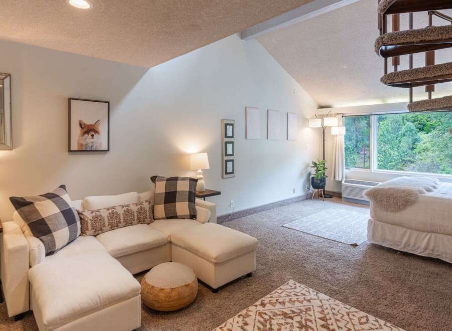 This charming living space features a comfortable sectional sofa adorned with checkered and patterned throw pillows, perfect for relaxing.