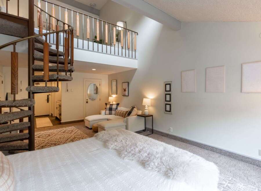 Experience unique living with this stunning loft-style bedroom featuring a dramatic spiral staircase leading to an upper level.