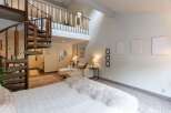 Experience unique living with this stunning loft-style bedroom featuring a dramatic spiral staircase leading to an upper level.