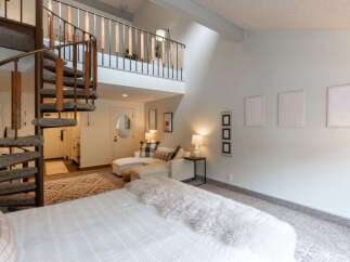 Experience unique living with this stunning loft-style bedroom featuring a dramatic spiral staircase leading to an upper level.