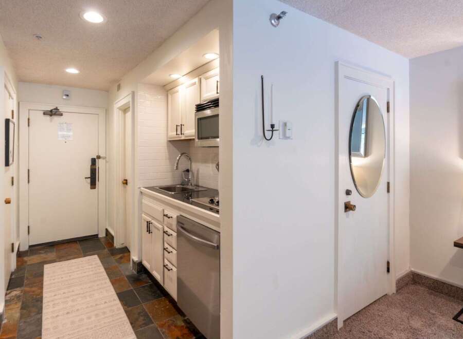 This charming hotel room features a compact kitchenette equipped with a microwave, sink, and dishwasher, perfect for preparing simple meals.