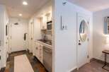 This charming hotel room features a compact kitchenette equipped with a microwave, sink, and dishwasher, perfect for preparing simple meals.