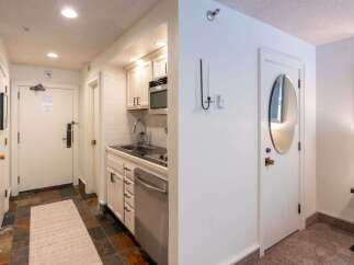This charming hotel room features a compact kitchenette equipped with a microwave, sink, and dishwasher, perfect for preparing simple meals.