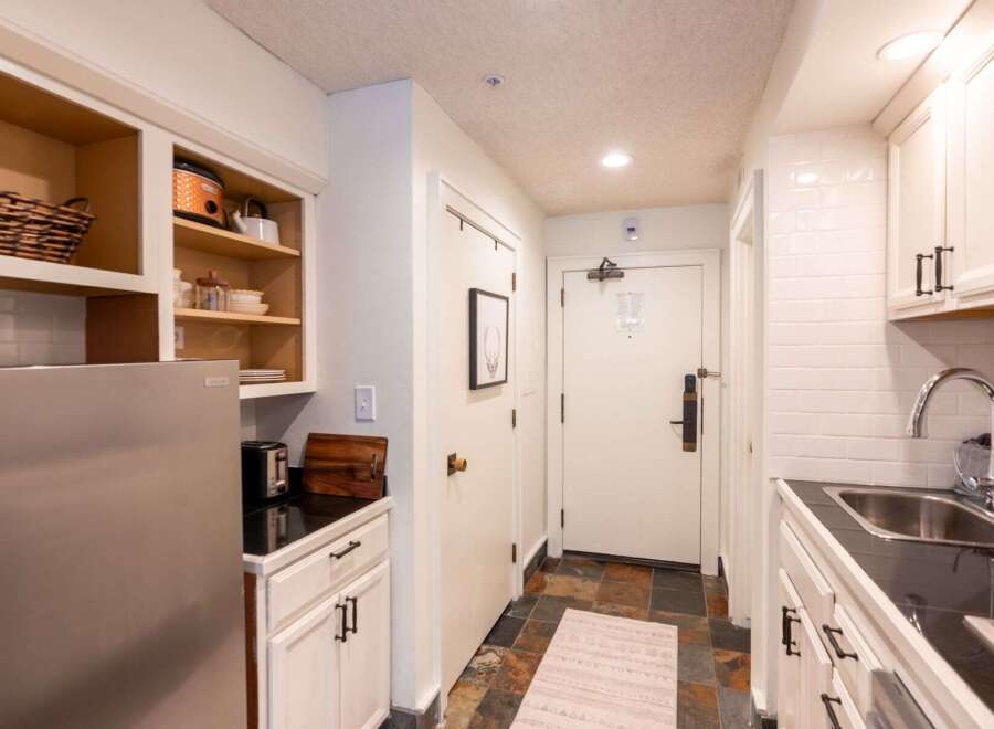 This charming kitchenette features a full-size stainless steel refrigerator and ample cabinet storage, perfect for preparing meals.