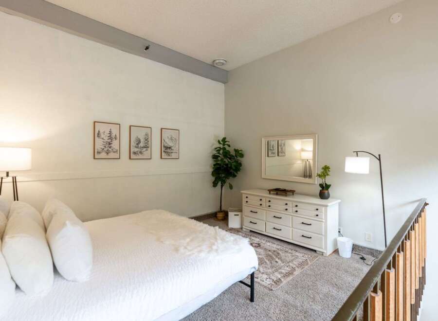 Discover this charming bedroom featuring a cozy bed adorned with plush white pillows and a soft throw.