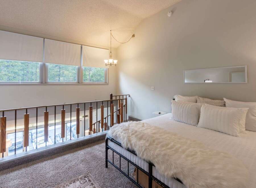 Experience elevated living in this charming loft bedroom, featuring a cozy bed adorned with plush white bedding and a luxurious faux fur throw.