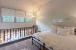 Experience elevated living in this charming loft bedroom, featuring a cozy bed adorned with plush white bedding and a luxurious faux fur throw.
