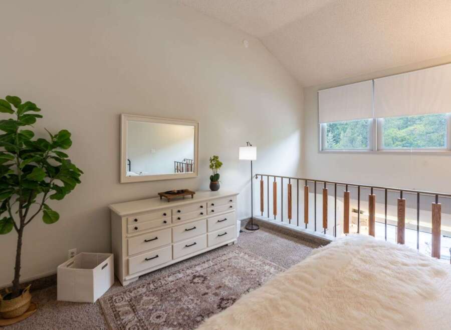 This charming bedroom features a spacious white dresser with a large mirror, perfect for storing your belongings and getting ready in style.