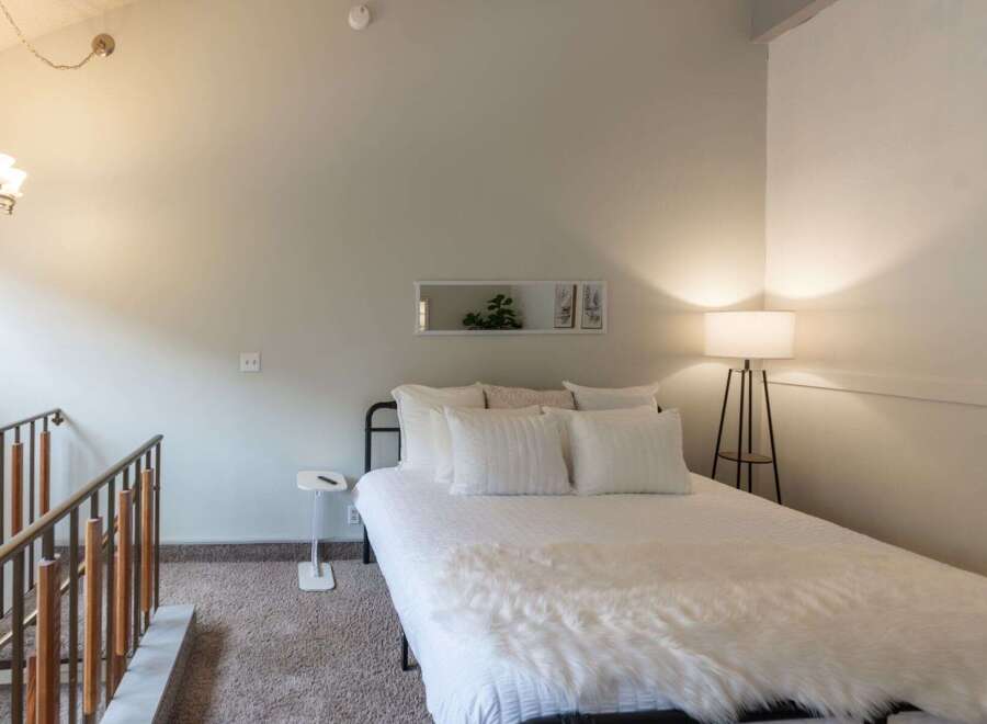 Discover this charming bedroom featuring a cozy bed adorned with plush white linens and a luxurious faux fur throw.