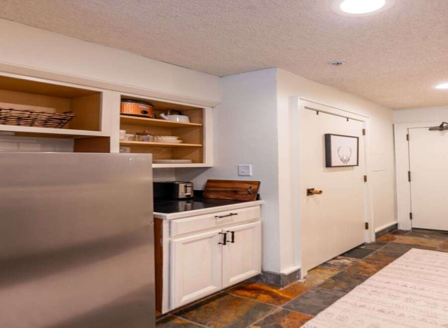 Discover this charming kitchenette featuring a stainless steel refrigerator and ample cabinet space for all your culinary needs.