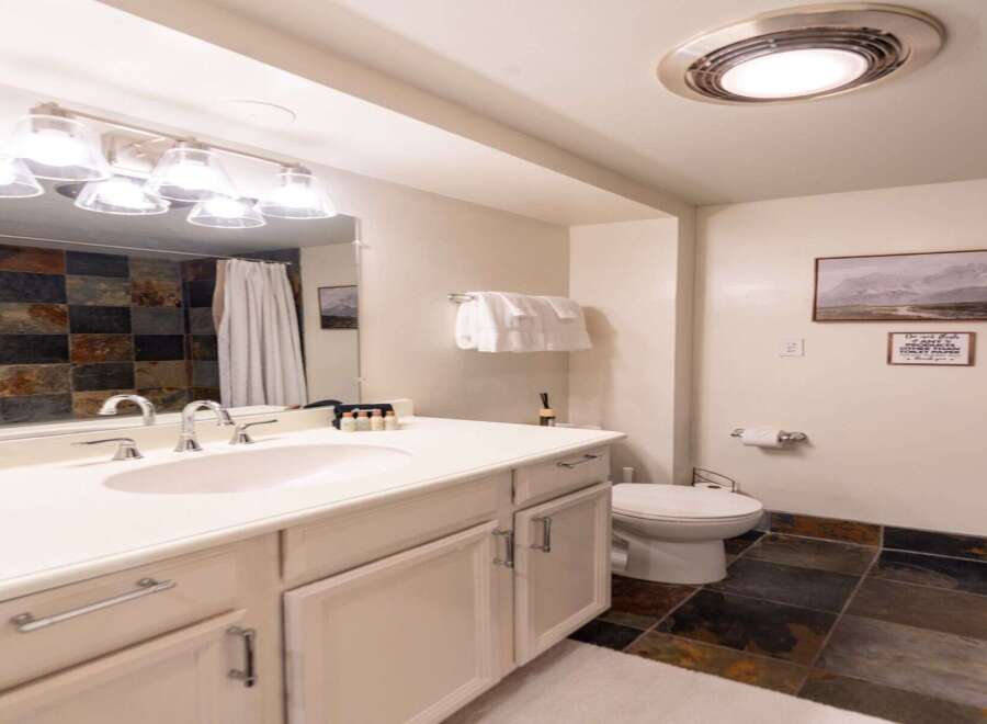 This charming bathroom features a spacious vanity with ample storage and a modern sink, complemented by a decorative tiled backsplash.