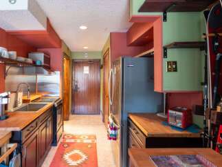 Discover this charming kitchen featuring warm wooden countertops and dark cabinetry, perfect for meal preparation.