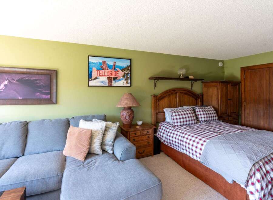 This charming bedroom features a cozy queen-size bed with a classic red and white plaid comforter, complemented by a matching headboard.