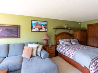 This charming bedroom features a cozy queen-size bed with a classic red and white plaid comforter, complemented by a matching headboard.