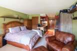 Experience cozy living in this charming studio apartment, featuring a comfortable queen-size bed with plaid bedding and a convenient kitchenette.