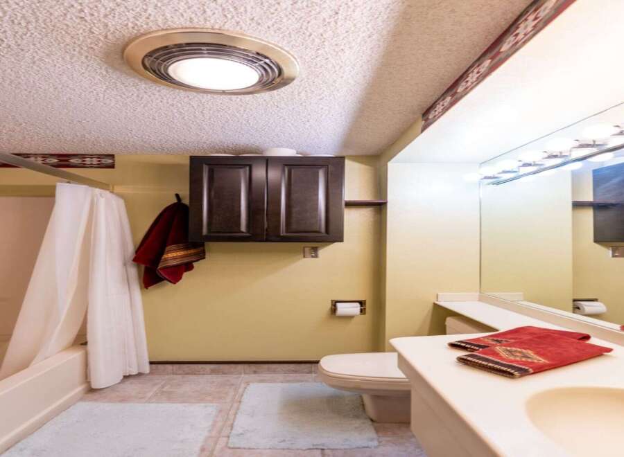This bathroom features a clean and functional design with a bathtub and shower combination, complemented by a dark wood cabinet for storage.