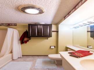This bathroom features a clean and functional design with a bathtub and shower combination, complemented by a dark wood cabinet for storage.
