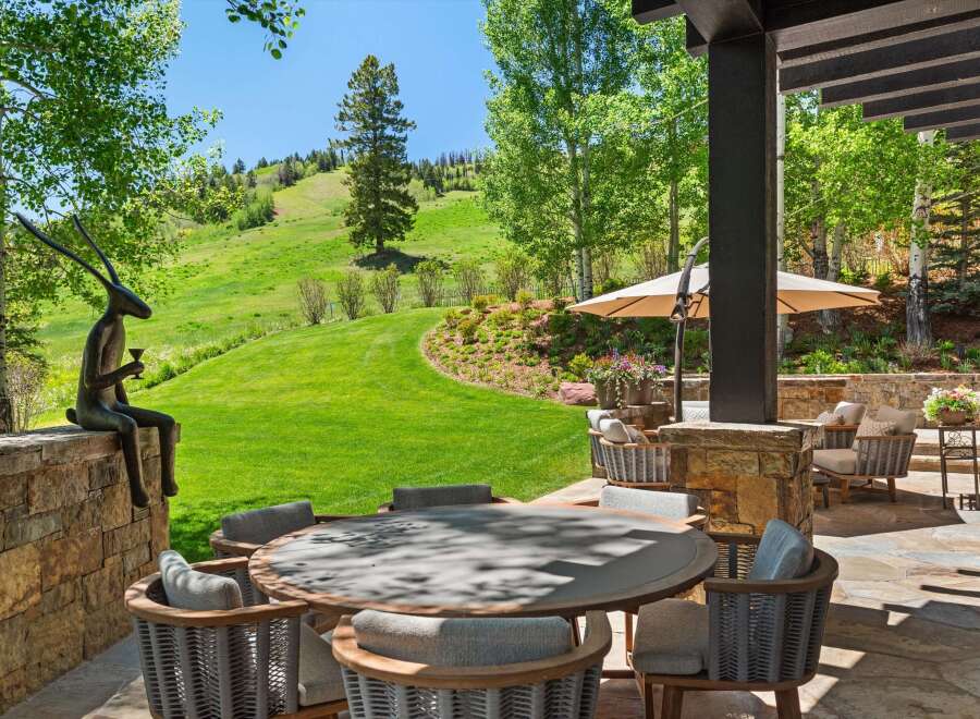 Experience luxurious outdoor living with this stunning patio featuring a round dining table and comfortable seating, perfect for al fresco meals.