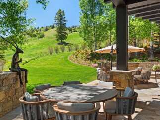 Experience luxurious outdoor living with this stunning patio featuring a round dining table and comfortable seating, perfect for al fresco meals.