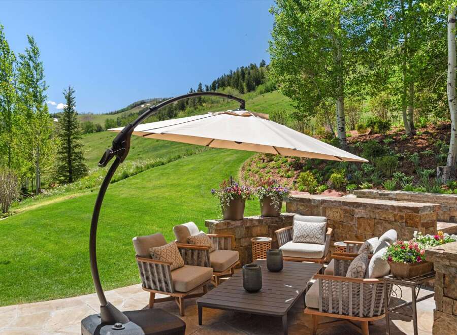 Enjoy breathtaking mountain views from this stunning outdoor living space, complete with a cantilever umbrella for shade and comfortable seating.