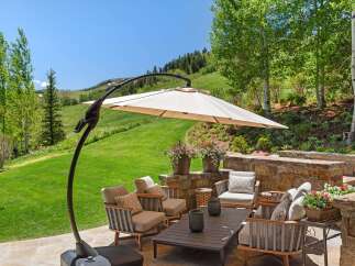 Enjoy breathtaking mountain views from this stunning outdoor living space, complete with a cantilever umbrella for shade and comfortable seating.
