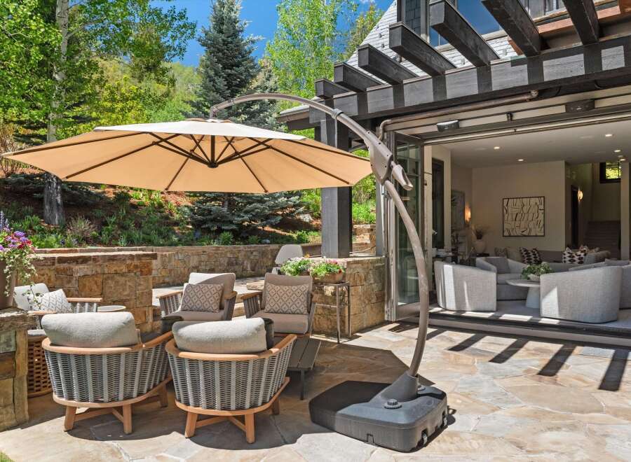 Enjoy outdoor living at its finest with this stunning patio featuring comfortable seating and a large cantilever umbrella for shade.