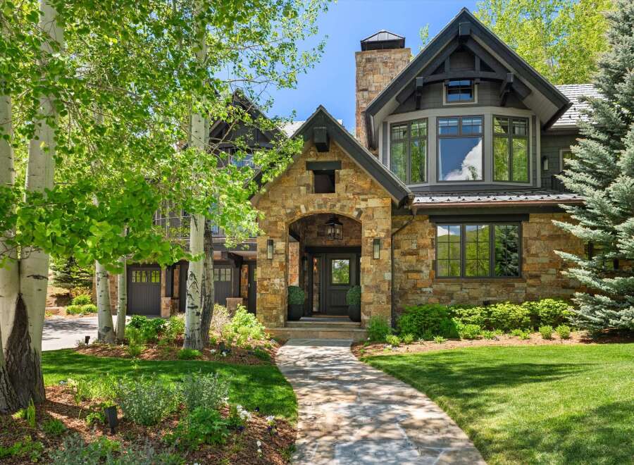 Discover this stunning mountain home featuring a grand stone entryway and a charming covered porch.