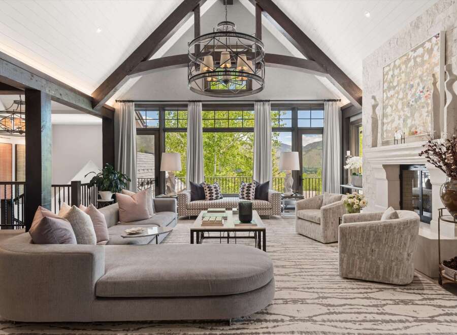 Experience luxury living in this stunning great room, featuring a vaulted ceiling with exposed beams and a grand stone fireplace.