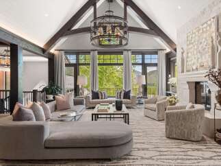 Experience luxury living in this stunning great room, featuring a vaulted ceiling with exposed beams and a grand stone fireplace.