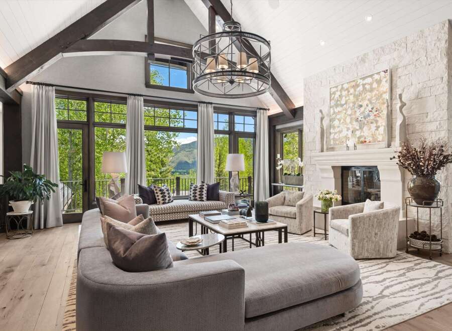 Experience luxurious mountain living in this stunning great room, featuring vaulted ceilings with exposed beams and a grand stone fireplace.