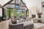 Experience luxurious mountain living in this stunning great room, featuring vaulted ceilings with exposed beams and a grand stone fireplace.