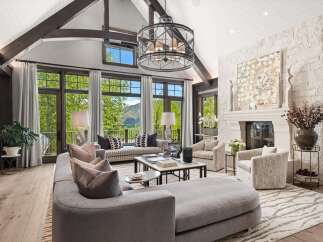 Experience luxurious mountain living in this stunning great room, featuring vaulted ceilings with exposed beams and a grand stone fireplace.
