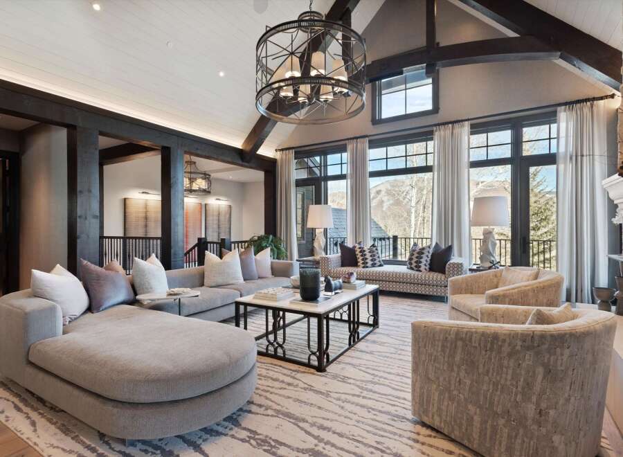 Experience luxurious mountain living in this stunning great room, featuring a grand sectional sofa and plush armchairs perfect for gathering.