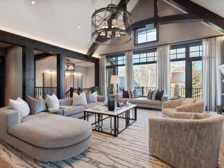 Experience luxurious mountain living in this stunning great room, featuring a grand sectional sofa and plush armchairs perfect for gathering.