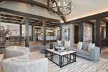 Experience luxurious living in this stunning open-concept great room, featuring exposed wooden beams and a grand chandelier.