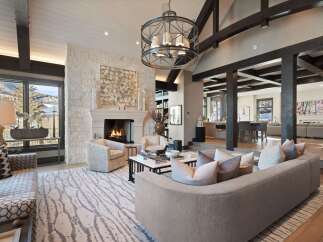 Experience luxury mountain living in this stunning great room, featuring a grand stone fireplace and soaring beamed ceilings.