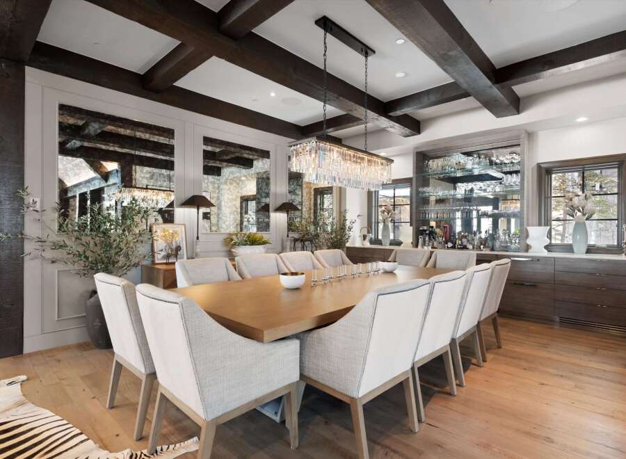 Experience elegant dining in this sophisticated space, featuring a grand wooden dining table surrounded by plush upholstered chairs.