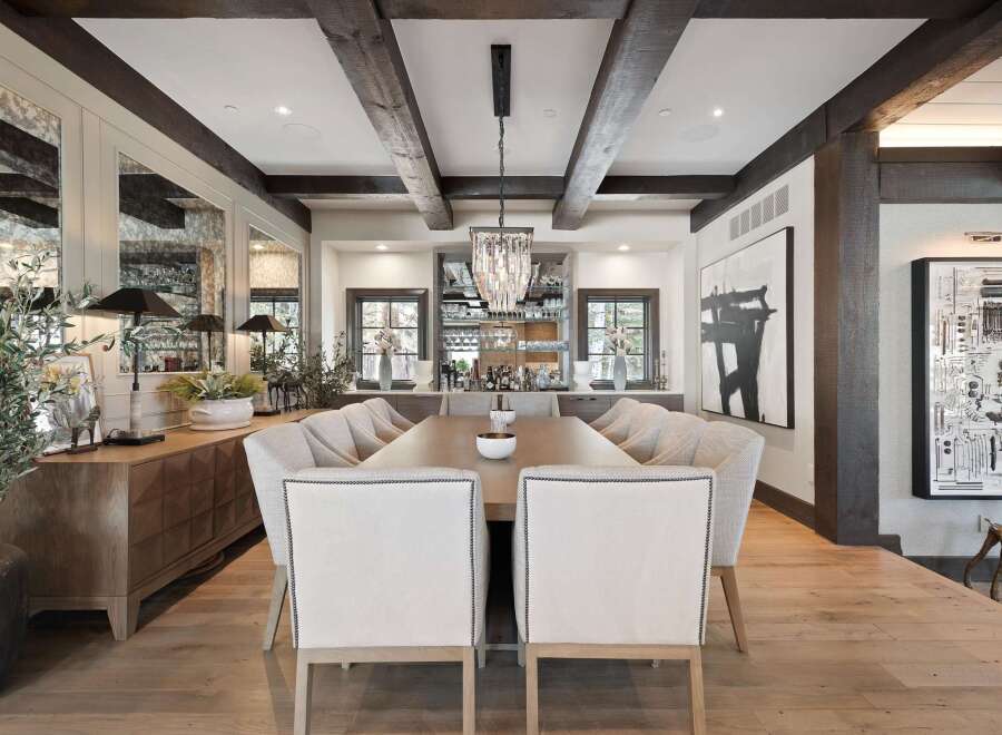 Experience luxurious dining in this elegantly appointed space, featuring a grand wooden table surrounded by plush upholstered chairs.