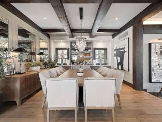 Experience luxurious dining in this elegantly appointed space, featuring a grand wooden table surrounded by plush upholstered chairs.