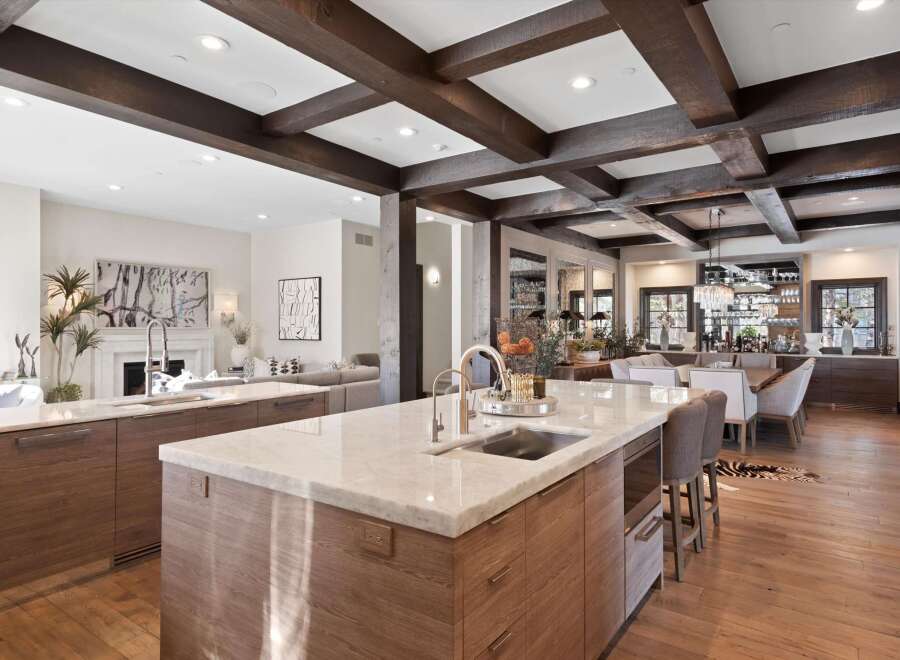 Experience luxury living in this stunning open-concept kitchen and dining area, featuring elegant marble countertops, custom wood cabinetry, and exposed wooden beams that add warmth and character.