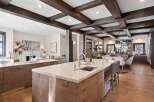 Experience luxury living in this stunning open-concept kitchen and dining area, featuring elegant marble countertops, custom wood cabinetry, and exposed wooden beams that add warmth and character.