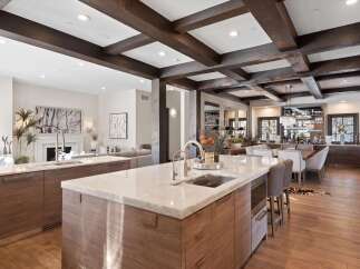 Experience luxury living in this stunning open-concept kitchen and dining area, featuring elegant marble countertops, custom wood cabinetry, and exposed wooden beams that add warmth and character.