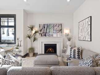 Cozy up by the fireplace in this inviting living room, featuring a marble surround and a vibrant abstract artwork.