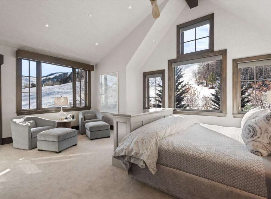 Experience breathtaking mountain views from this luxurious bedroom, featuring expansive windows that showcase a serene winter landscape.
